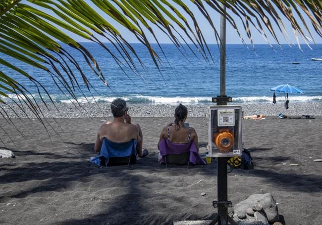 Usuarios en la playa de Puerto Naos justo al lado de un medidor de CO2.