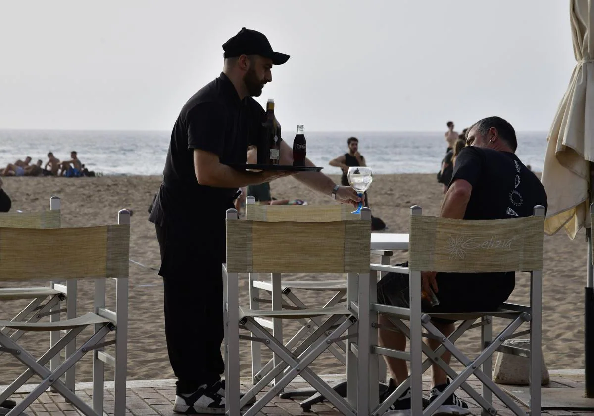 Un trabajador del sector turístico en un negocio en la playa de Las Canteras.