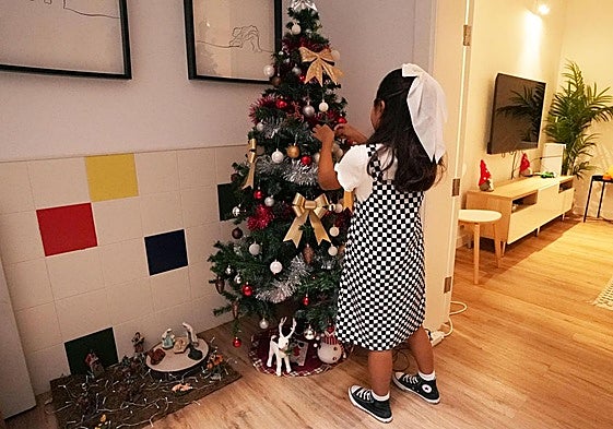 Una niña decora el árbol de Navidad en Casa Pipa, el albergue de la Fundación Pequeño Valiente.