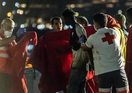 Trabajadores de la Cruz Roja reciben a las personas de un cayuco rescatadas por una embarcación de Salvamento Marítimo, en el muelle de Arguineguín.