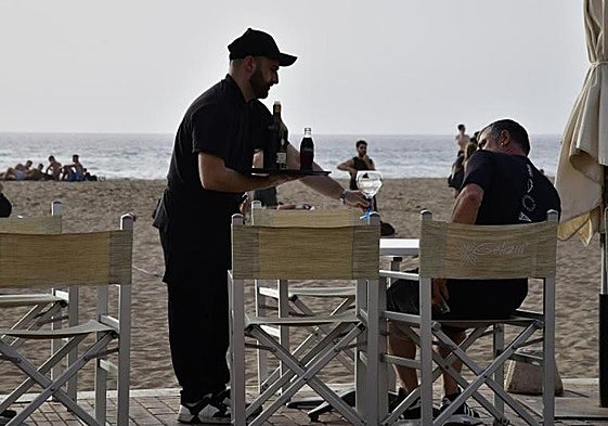 Un camarero atiende a un cliente en la Playa de Las Canteras.