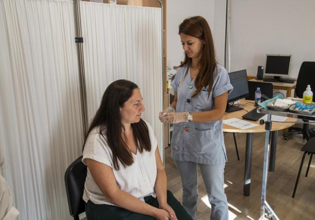 Foto de archivo de una enfermera del SCS disponiéndose a vacunar contra la gripe a una mujer.