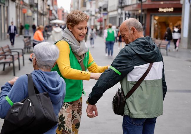 Una voluntaria coloca un brazalete a un ciudadano.