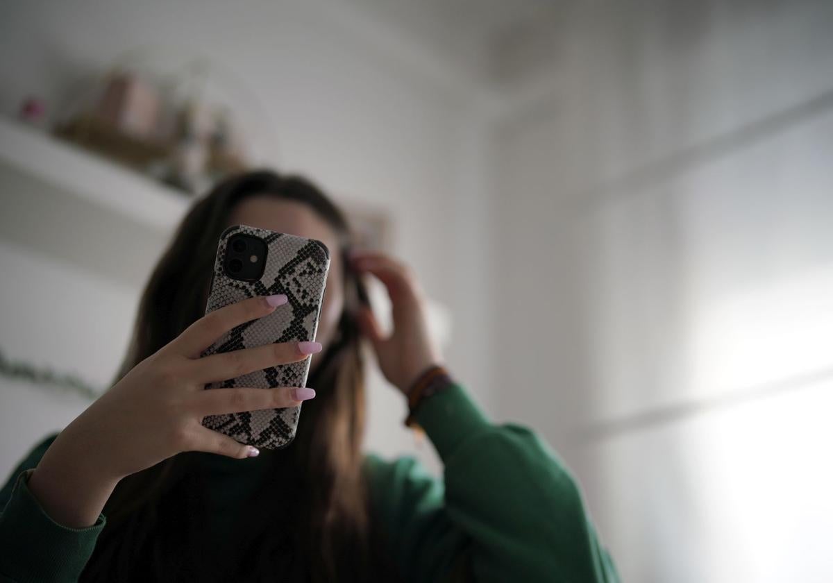 Una adolescente usando el teléfono móvil.