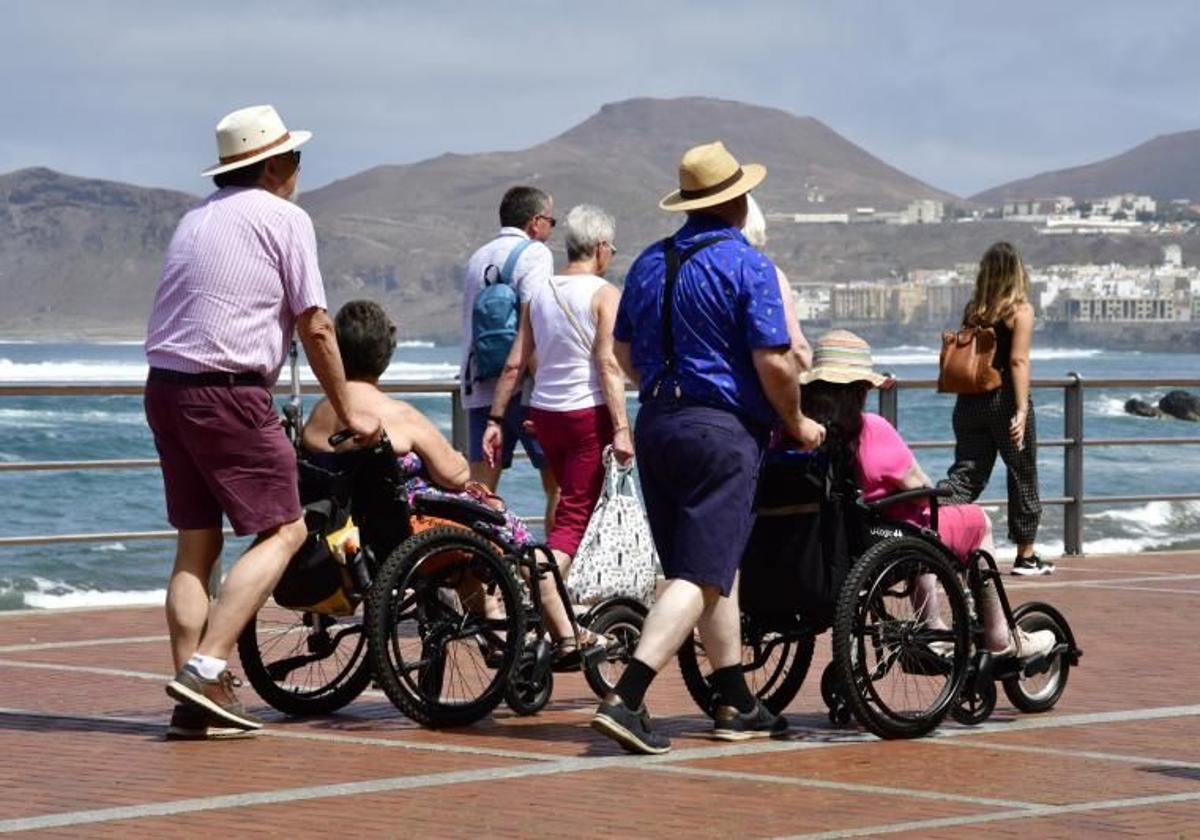 Foto de archivo de un grupo de personas, algunas con movilidad reducida, paseando por Las Canteras.