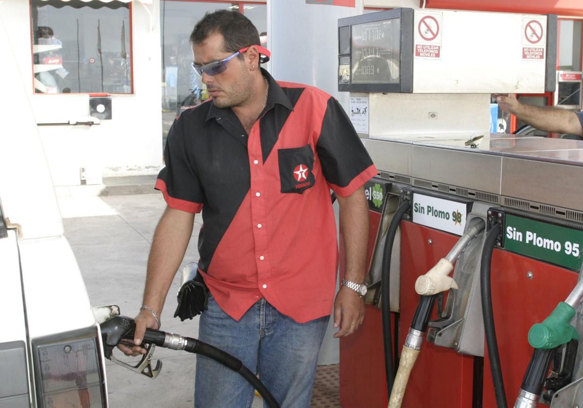 El operario de una gasolinera llena el tanque de un vehículo.