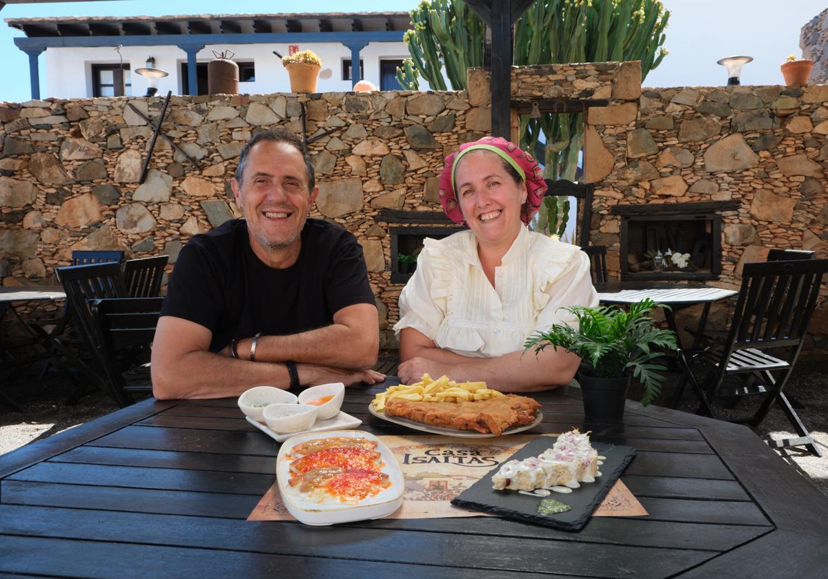 Marcos y Moni, con tres de sus platos estrella: el cachopo, la ensaladilla de sancocho con la forma de la isla y el queso asado.