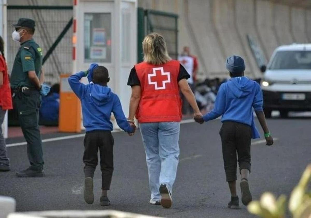 Foto archivo de una trabajadora de Cruz Roja atiende a dos menores migrantes en El Hierro.