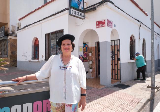 Delia León, con la gorra que usaba Antoñito El Dulcero, en la esquina de la dulcería, con un vecino esperando por ella para charlar por la ventana.