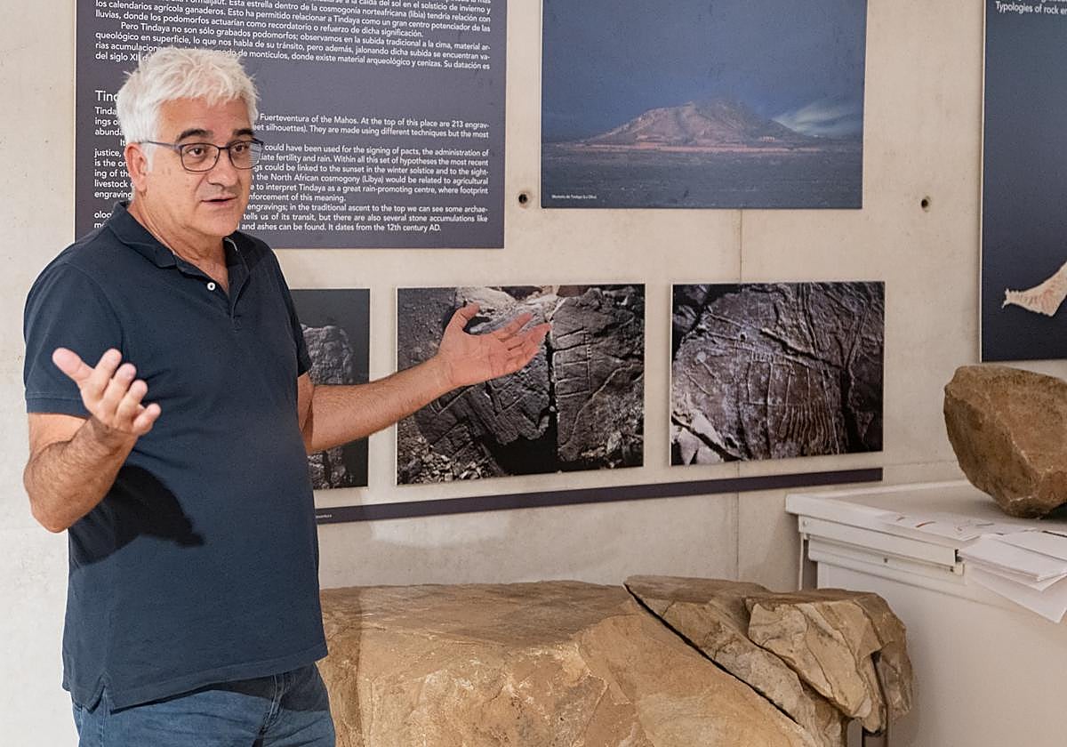 Valentín Barroso, director de Arqueocanaria, en el ciclo Entre Vitrinas del Museo Arqueológico de Fuerteventura, al lado de un panel de podomorfos.