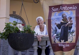 Natasha Betancor, apoyada en la balaustrada, se asoma junto al cartel que anuncia las fiestas.