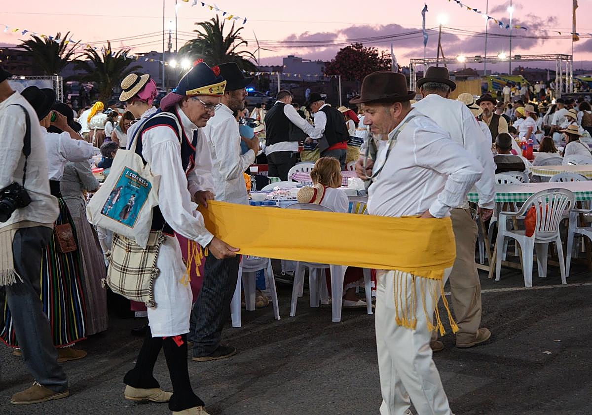 Imagen principal - Instrucciones para ponerse los complementos de la indumentaria canaria se dieron en varios puntos del baile.
