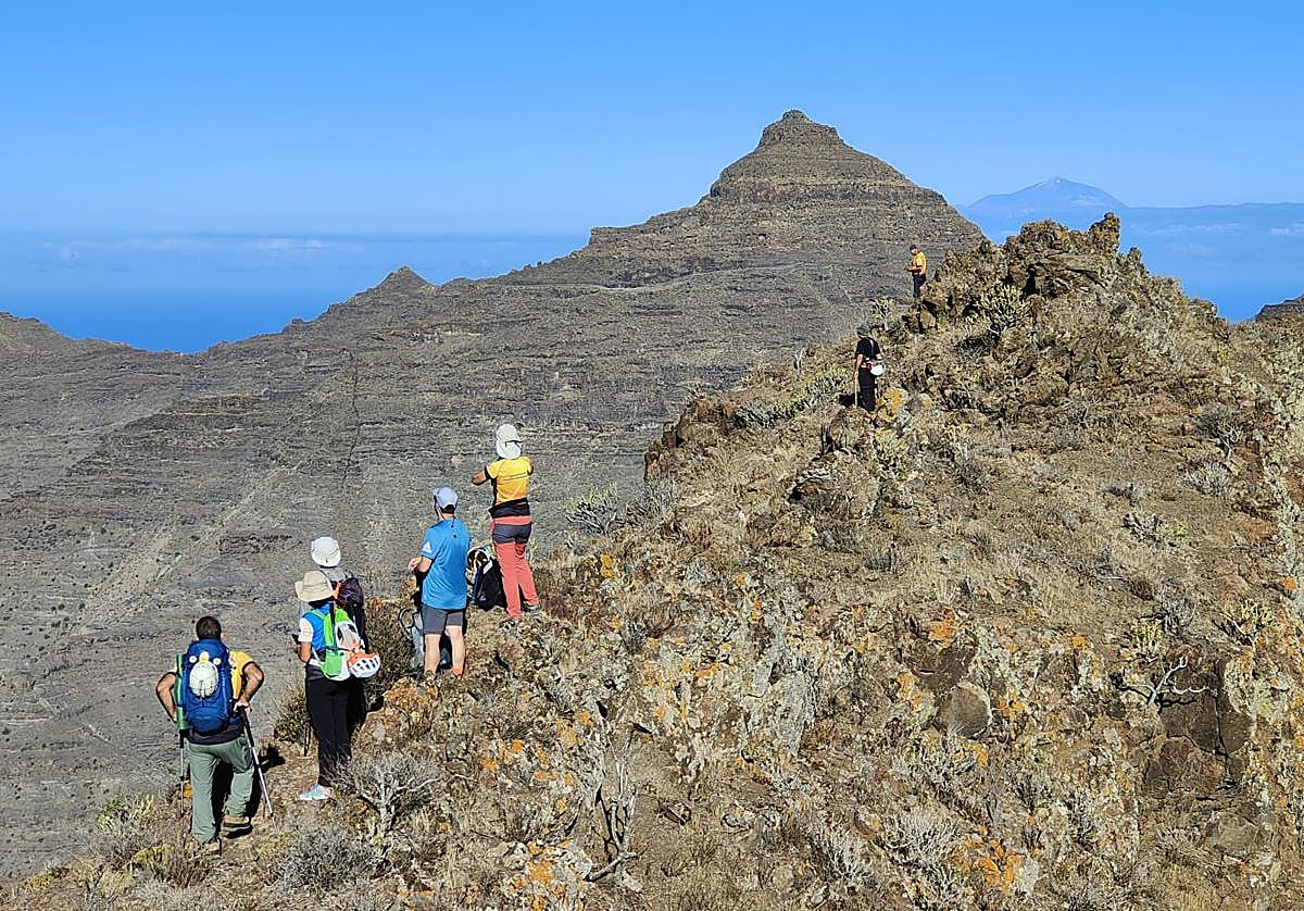 Imagen de un grupo de montañeros en el oeste de Gran Canaria, con el Teide al fondo.