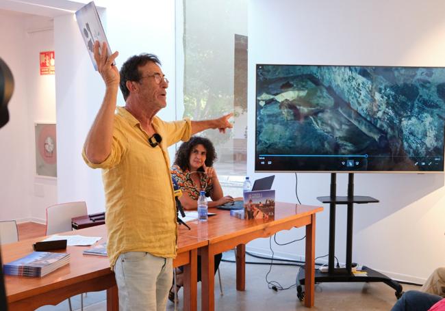 El autor, durante la presentación del libro, con una imagen de una piel en la tenería.
