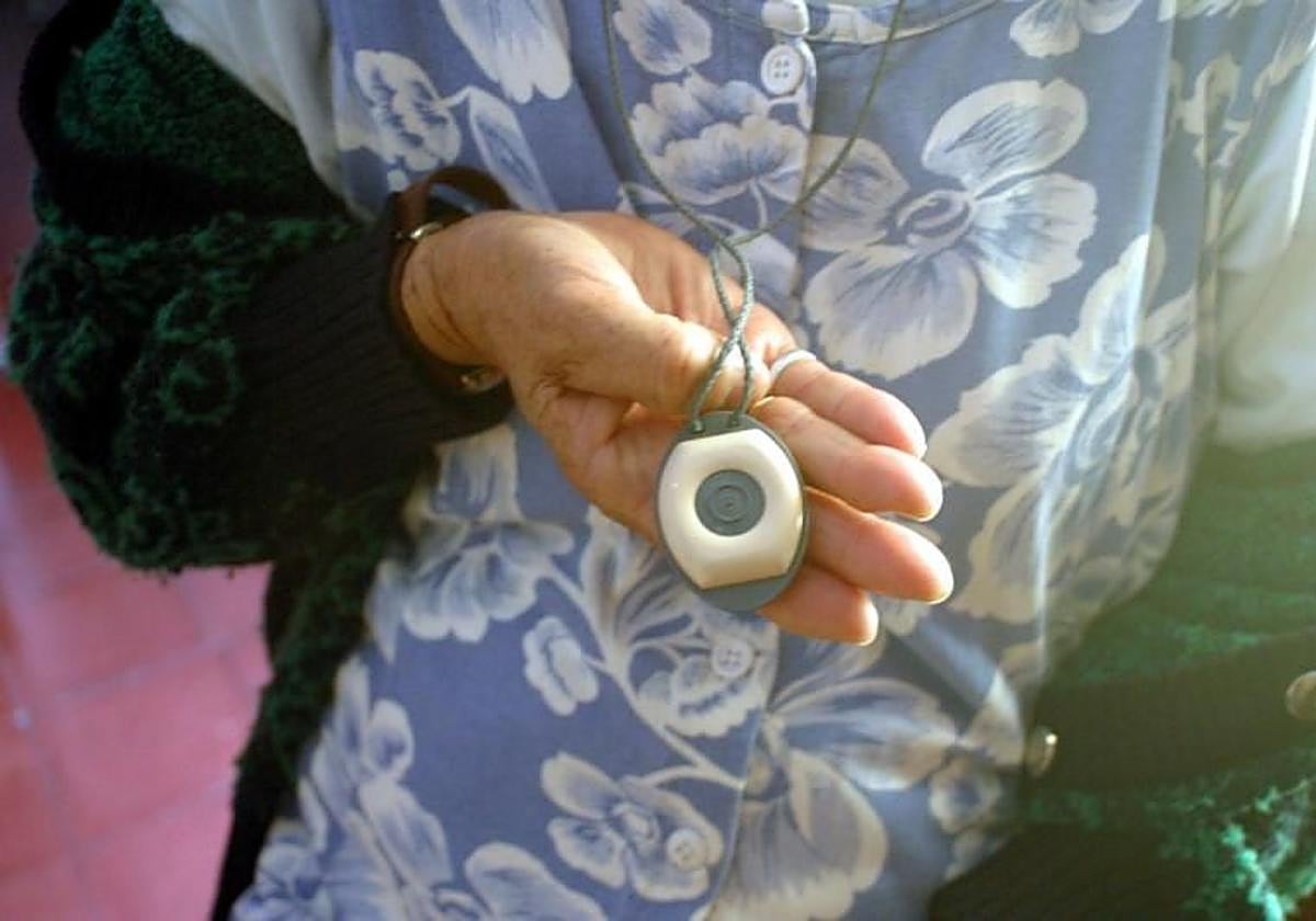 Una mujer dependiente muestra un botón de teleasistencia.