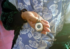 Una mujer dependiente muestra un botón de teleasistencia.