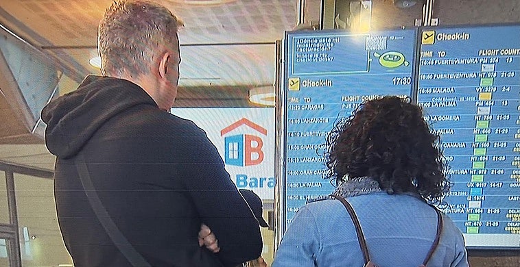 Dos pasajeros mirando el estado de su vuelo en el Aeropuerto de Tenerife.