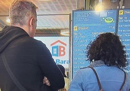 Dos pasajeros mirando el estado de su vuelo en el Aeropuerto de Tenerife.