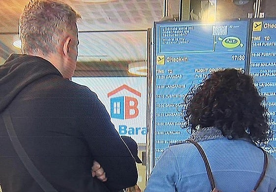 Dos pasajeros mirando el estado de su vuelo en el Aeropuerto de Tenerife.