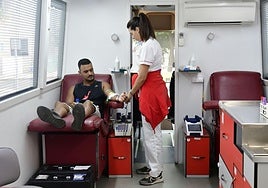 Un hombre dona sangre en una unidad móvil.