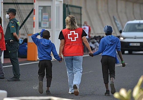 Menores migrantes acompañados por una voluntaria de Cruz Roja.