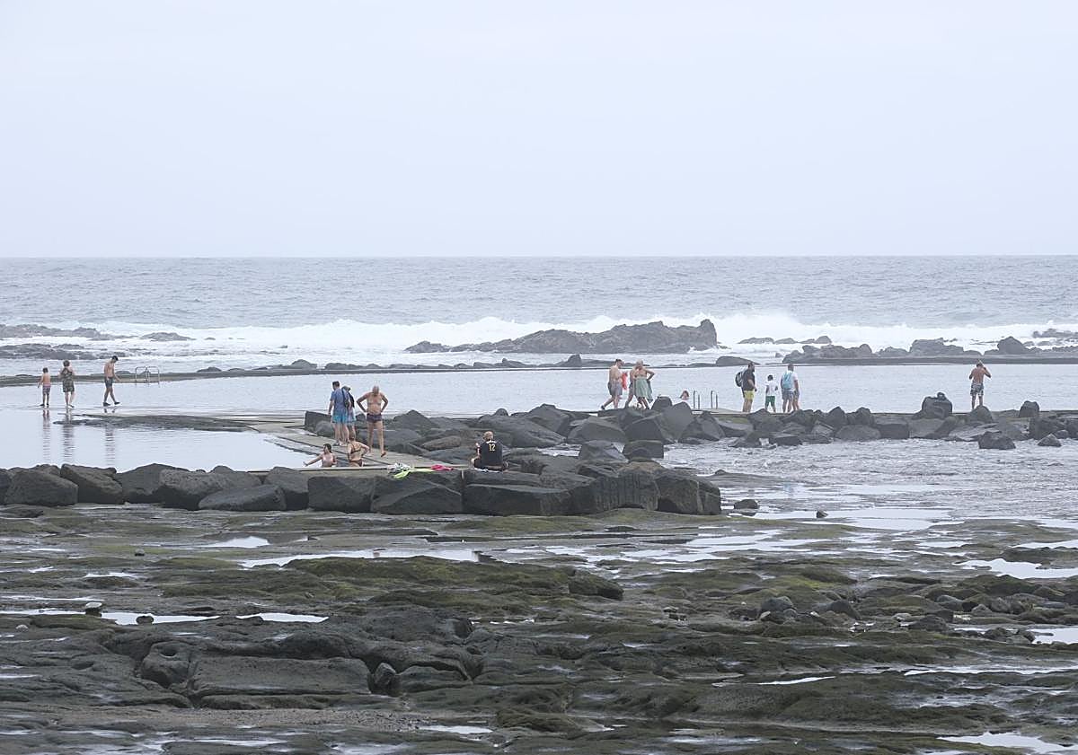 Imagen principal - Los bañistas disfrutando de los charcos de El Puertillo, la estatua de bronce de Sandokán en el paseo de la playa y las olas rompen con las rocas de la costa.