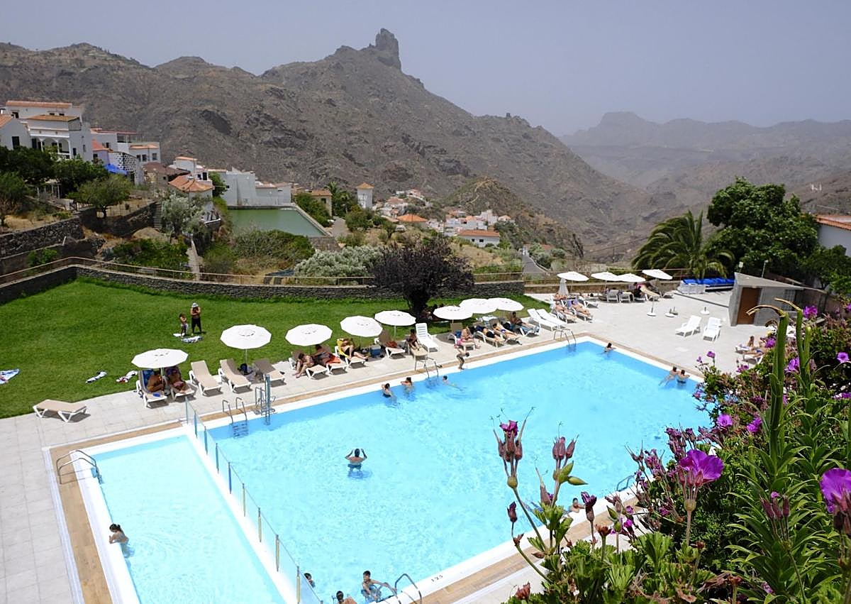 Imagen secundaria 1 - 1. Una pareja de visitantes en el mirador de la Plaza de Nuestra Señora del Socorro. 2. Un grupo de personas disfruta de la piscina municipal de Tejeda, con vistas al Roque Bentayga. 3. Una pareja de turistas camina de la mano por una de las principales calles de Tejeda.
