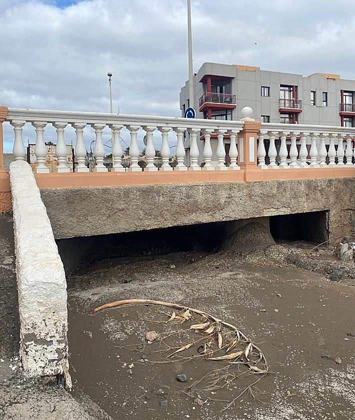Imagen secundaria 2 - En la imagen superior, tres pequeños tubos, ahora taponados, por los que, se supone, ha de pasar el agua que baja por Las Manolitas. Debajo, efecto represa de varios postes en un punto donde una edificación redujo a un pasadizo al barranco de Las Manolitas. Y finalmente, boca de apenas 50 o 60 centímetros por la que la playa de Salinetas espera que pase todo lo que baje por el barranco.