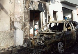 Imagen del coche y la fachada quemados.