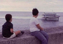 Dos niños observan a lo lejos la llegada del jetfoil.