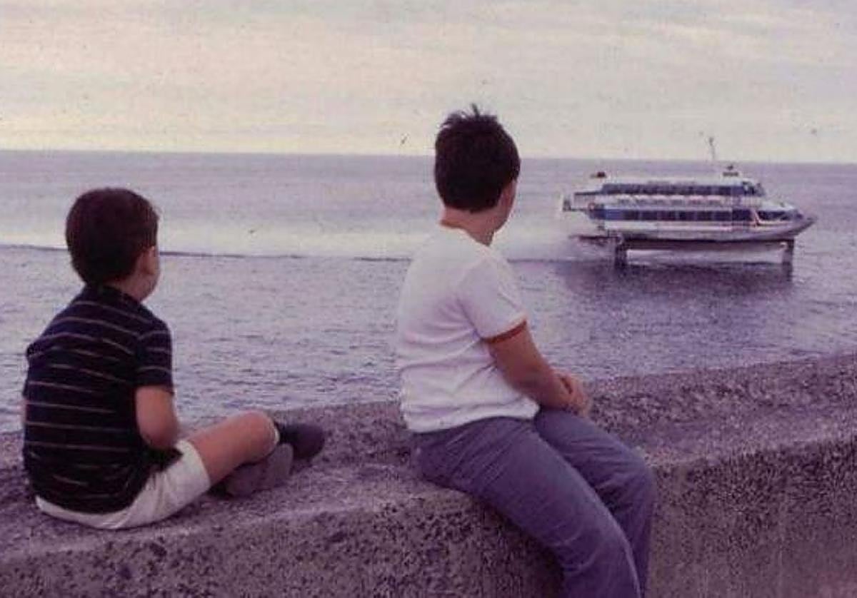 Dos niños observan a lo lejos la llegada del jetfoil.