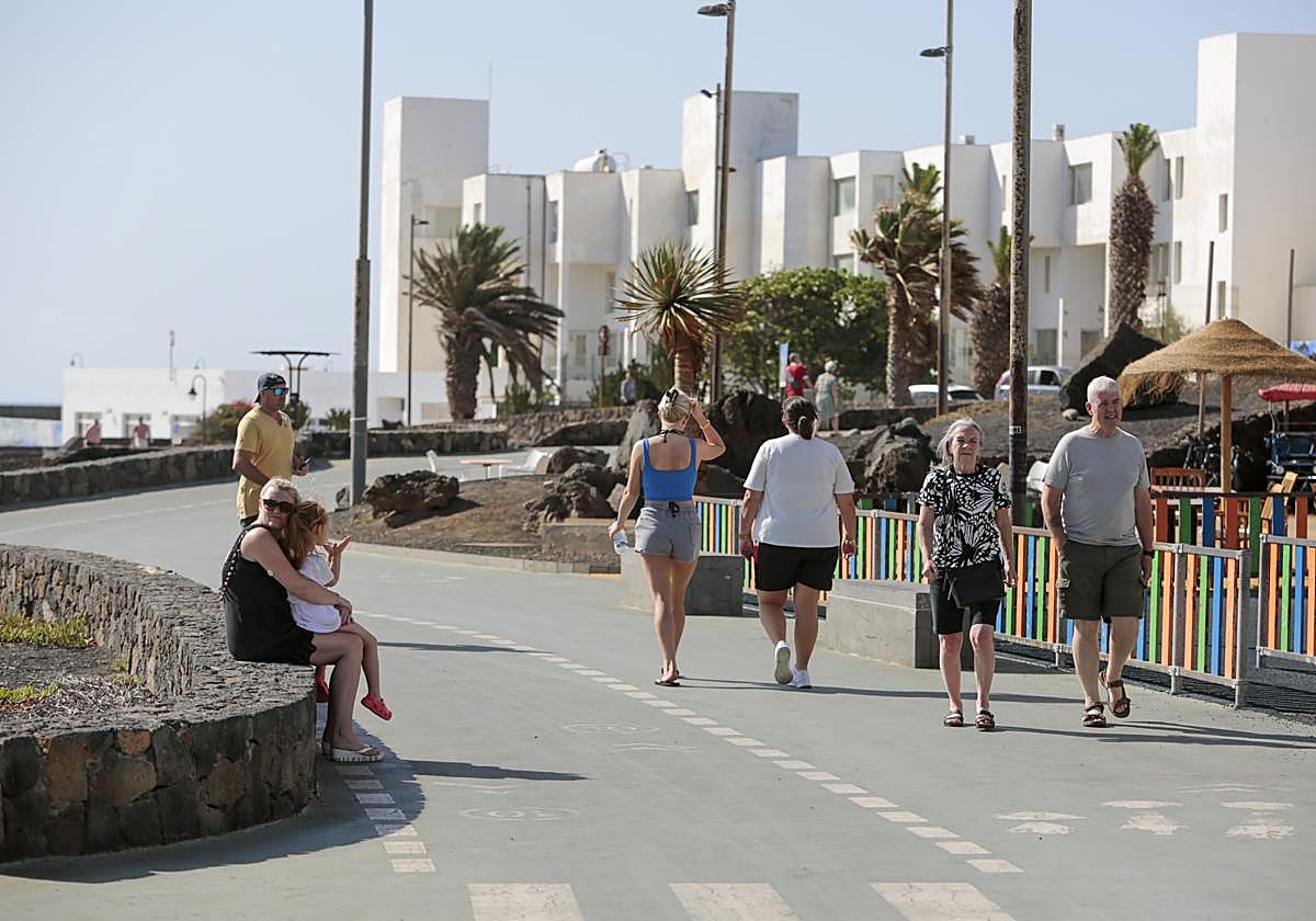 Turistas disfrutando de un paseo por un espacio de primera línea en Costa Teguise.