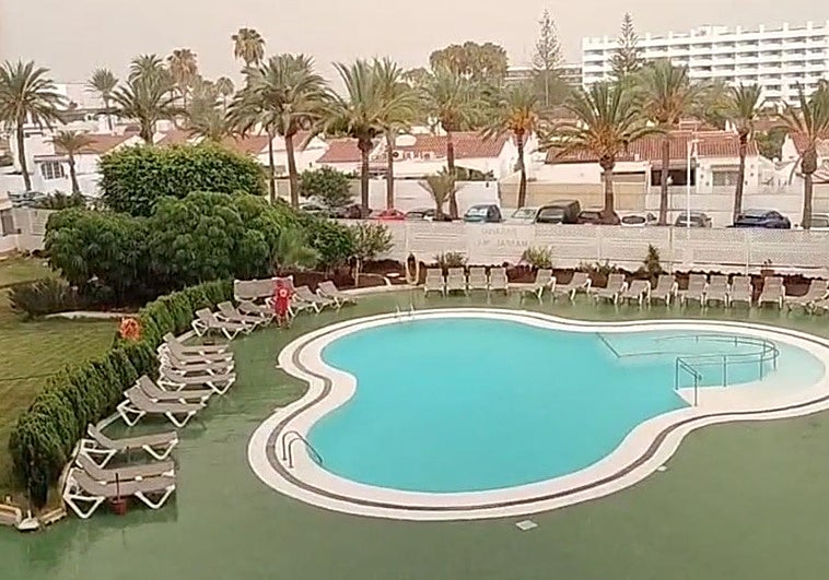 Un socorrista recoge las hamacas de una piscina de Maspalomas bajo el cielo encapotado.