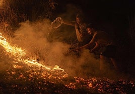 Vecinos de la localidad trabajan la madrugada de este domingo en labores de extinción del incendio forestal de A Rúa (Ourense).
