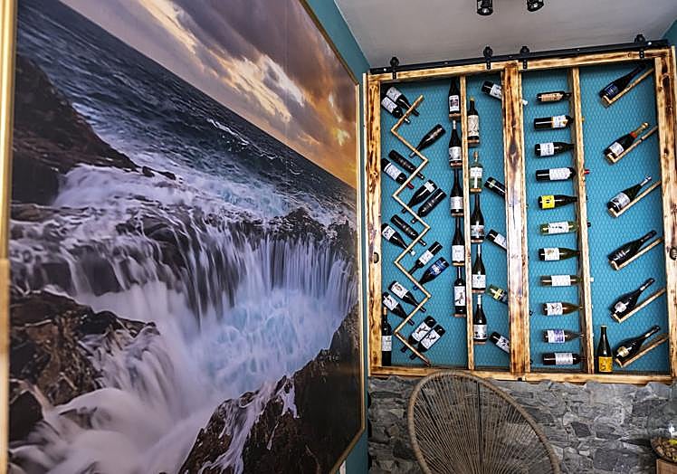 Vinoteca hecha a mano por Jorge Medina junto a una fotografía del bufadero de Telde.