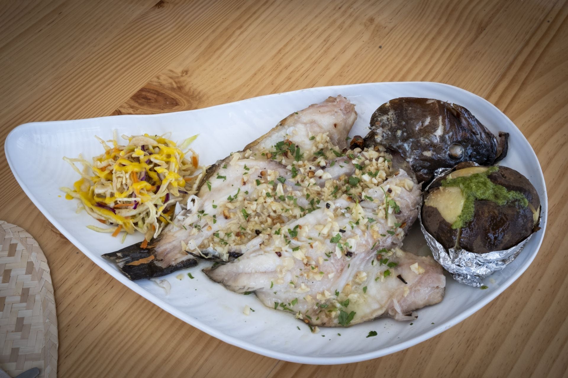 Mero a la donostiarra acompañado con ensalada de col, vinagreta de mango y papas.