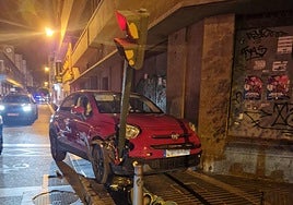 Imagen del coche empotrado entre la fachada del edificio y el semáforo.
