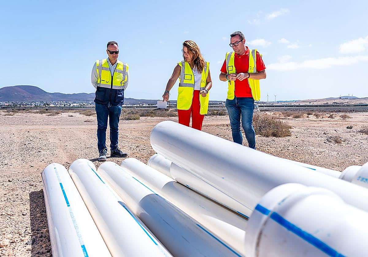 La presidenta majorera Lola García, flanqueada por el consejero de Aguas, Adargoma Hernández, y el gerente del CAAF, Francisco Javier Hormiga, con las nuevas tuberías.
