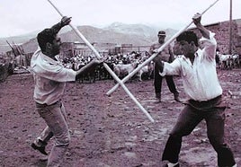 Foto antigua de dos personas practicando el Juego del Garrote Tradicional.