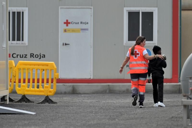 Un menor migrante junto a una trabajadora de Cruz Roja en el muelle de La Restinga.