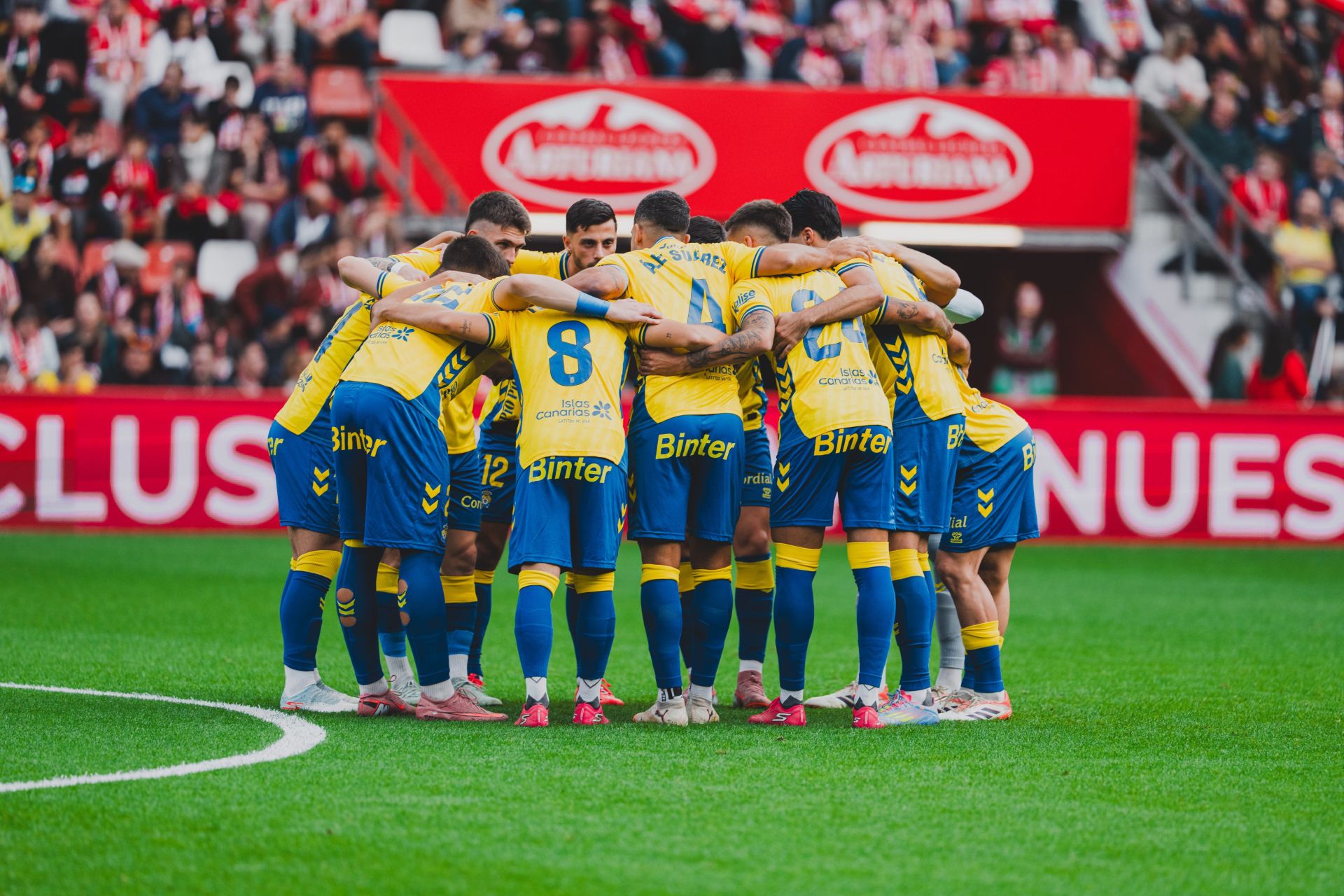 Piña de los jugadores de la UD en el césped del estadio del Sporting poco antes del inicio del encuentro del pasado domingo.
