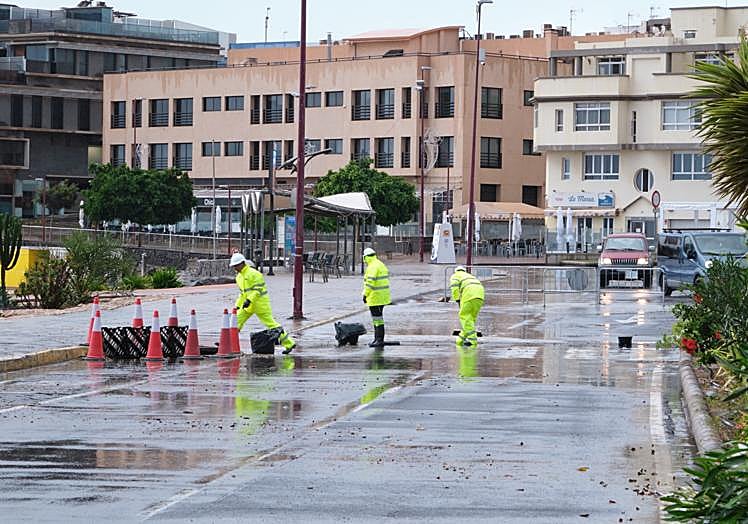Operarios retiran las piedras del tramo de avenida marítima de Puerto del Rosario que se cortó por la lluvia, a la altura de la playa de los Pozos.