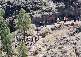 Senderistas llegando al Roque Nublo por un sendero que pasa por el macizo rocoso.