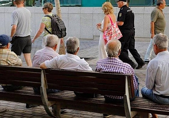 Imagen de archivo de varios hombres sentados en un banco.