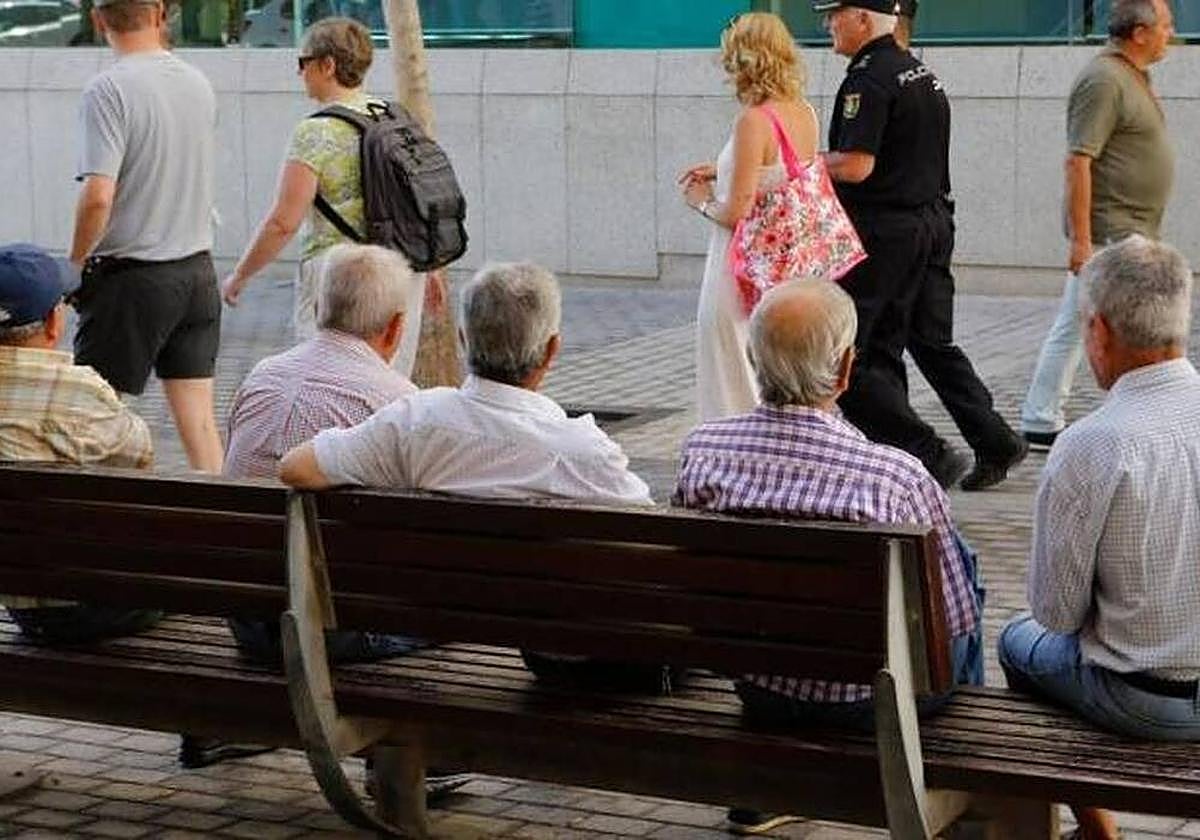 Imagen de archivo de varios hombres sentados en un banco.