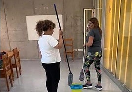 Dos usuarias del centro pasan la fregona al piso.