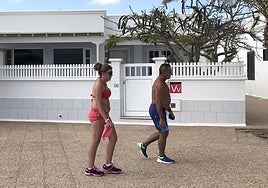 Dos personas pasan ante un inmueble destinado a la vivienda vacacional en Playa Honda, Lanzarote.