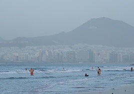 Las Canteras recibe a algunos bañistas en la tarde de este lunes, con la calima de fondo.