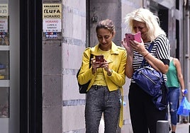Dos mujeres mirando su móvil en la calle.