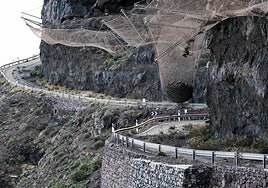 Vista parcial del tramo cerrado de la GC-200 donde se aprecia la bola de piedras suspendida en una malla de contención.